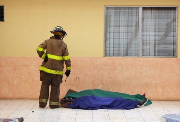 Handout picture released by Guatemalan Volunteer Firefighters showing a firefighter looking to the corpses of two of the 20 victims of a fire at children's shelter Virgen de la Asuncion facility, in San Jose Pinula, about 10 kilometres east of Guatemala City, on March 8, 2017. At least 20 teenage girls died in a fire at a children's shelter in Guatemala, a spokesman for the local fire service said. It was not immediately known how many of the bodies were those of children. The center, supervised by state social welfare authorities, hosts minors who are victims of family mistreatment. The facility has been the target of multiple complaints alleging abuse, and several children have run away. / AFP PHOTO / Guatemalan Volunteer Firefighters / HO / RESTRICTED TO EDITORIAL USE - MANDATORY CREDIT "AFP PHOTO /Guatemalan Volunteer Firefighters /HO " - NO MARKETING - NO ADVERTISING CAMPAIGNS - DISTRIBUTED AS A SERVICE TO CLIENTS