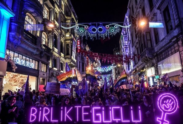 People hold a neon sign reading "Together, stronger" as they march down Istiklal Avenue during a feminist night march to mark International Women's Day in Istanbul on March 8, 2017. / AFP PHOTO / OZAN KOSE