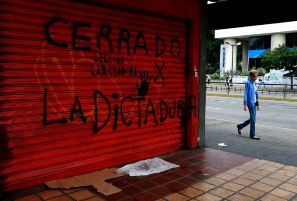Una mujer pasa junto a un comercio cerrado por la huelga, ayer en Caracas. MARCO BELLO REUTERS